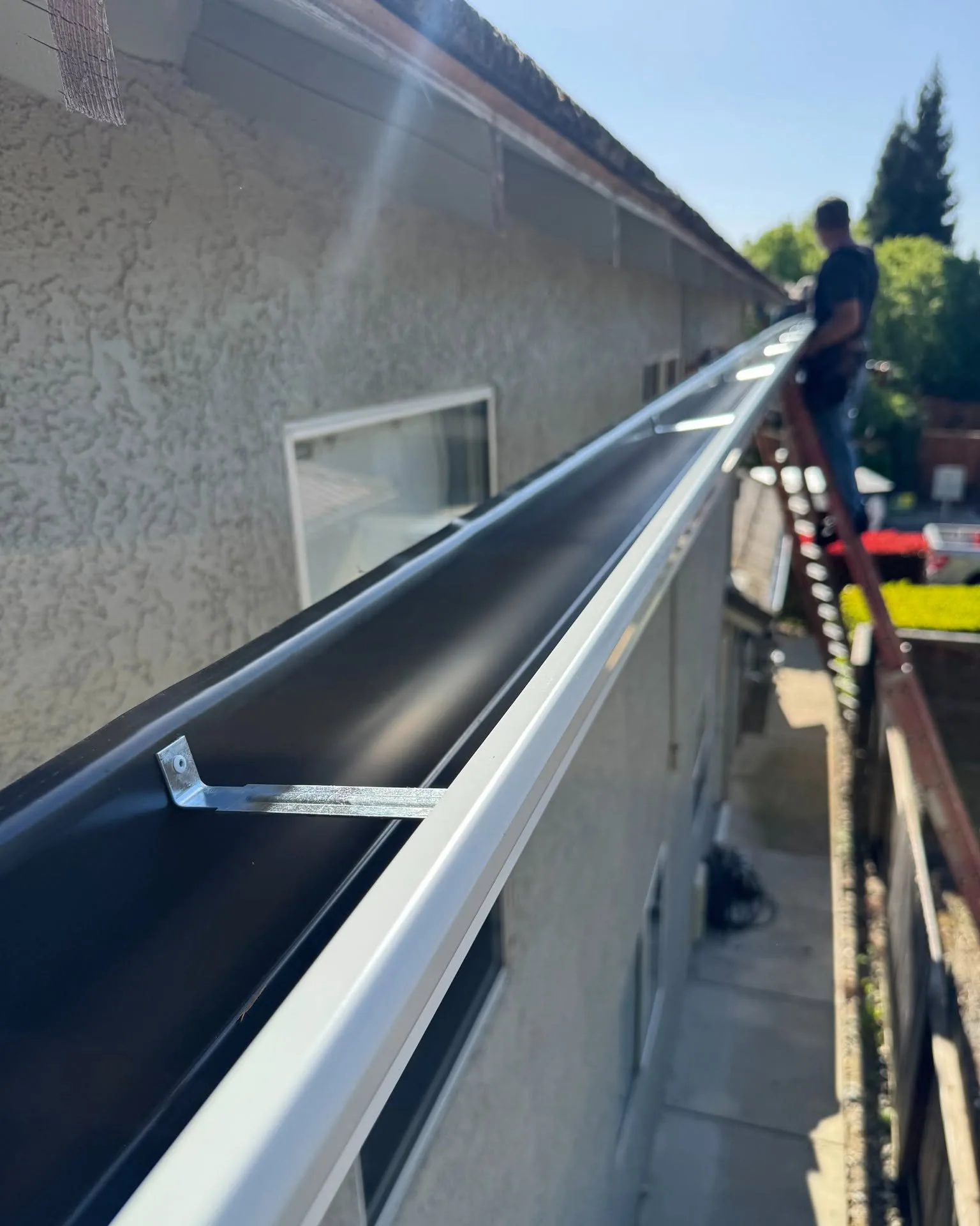 Dunzo Gutters technician installing a new hanger bracket on a Sacramento home during a gutter repair
