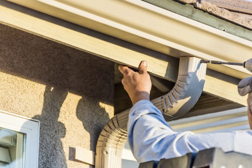 Dunzo Gutters technician drilling a new gutter hanger into the fascia on a Sacramento home