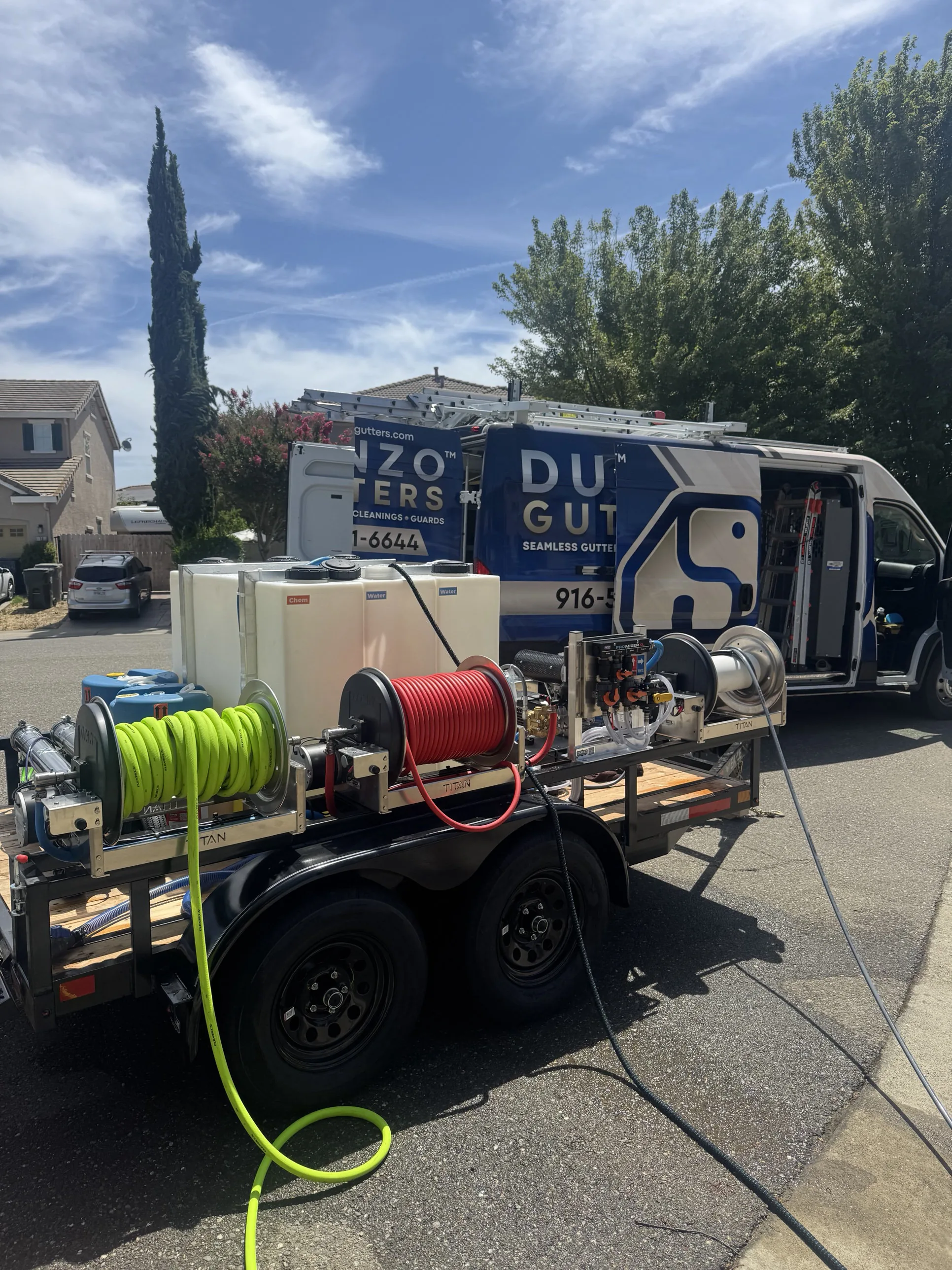 The Dunzo Gutters van and soft-wash equipment trailer, with chemical and water tanks visible