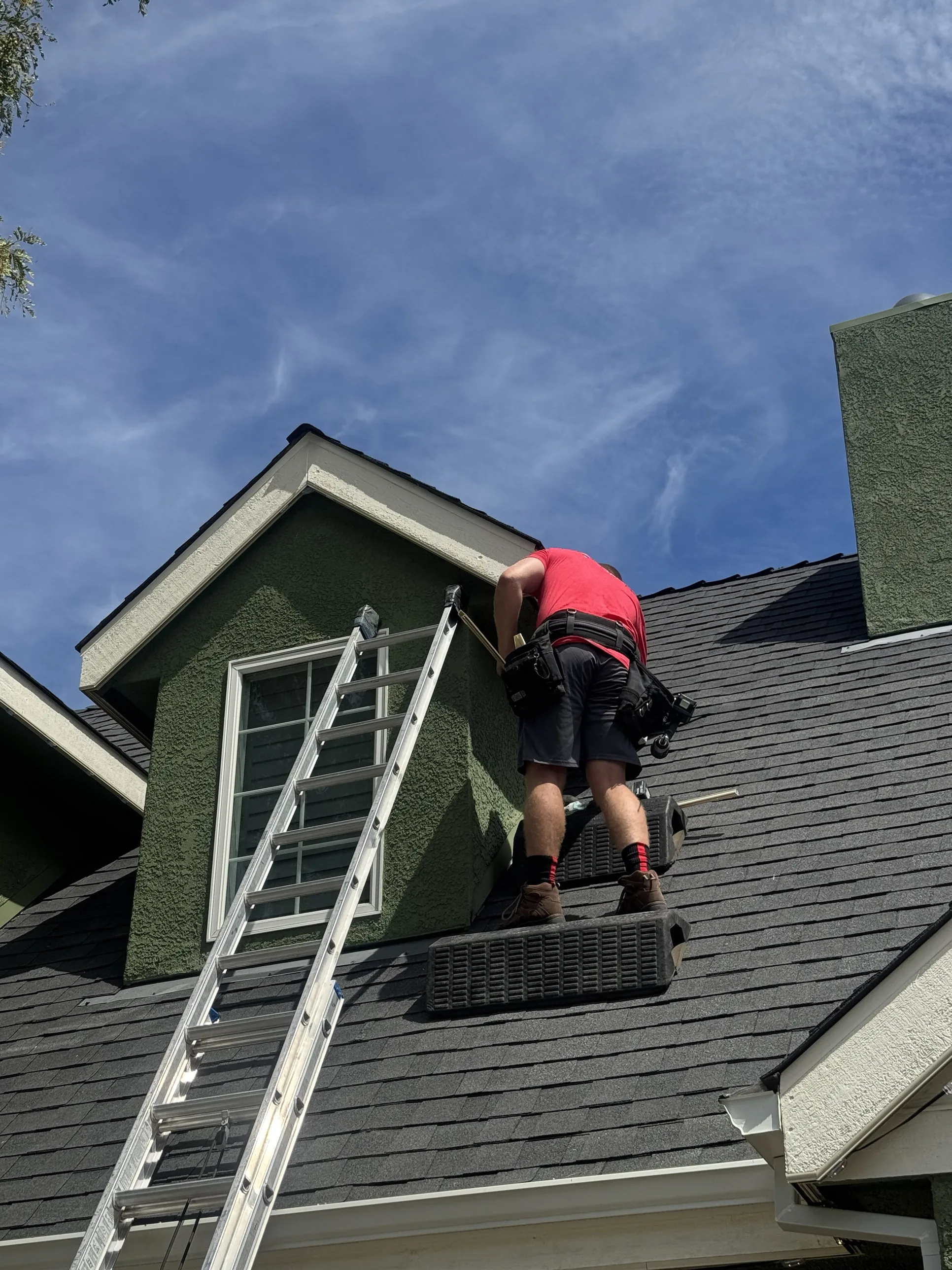 A Dunzo Gutters technician working on a roofline near a dormer window