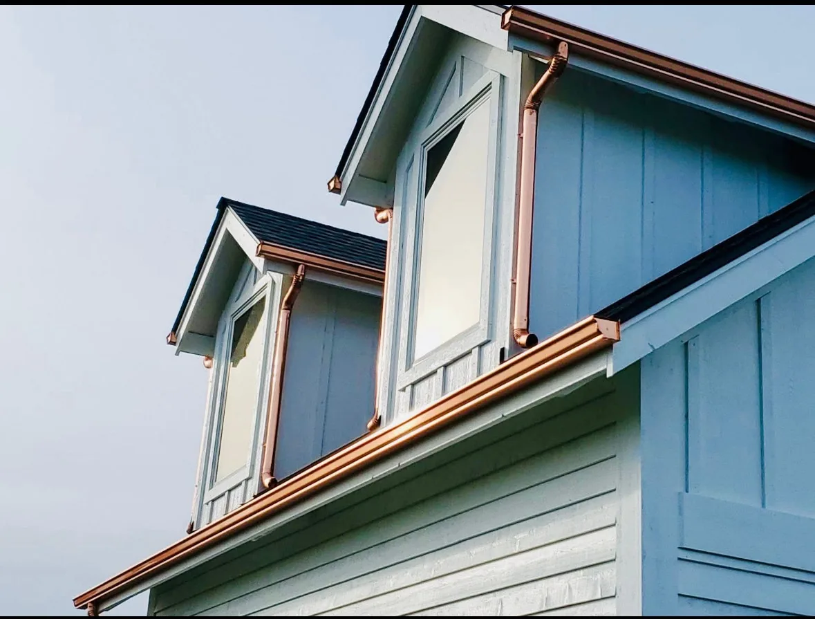 Copper seamless gutters and downspouts on a home's custom dormer roofline