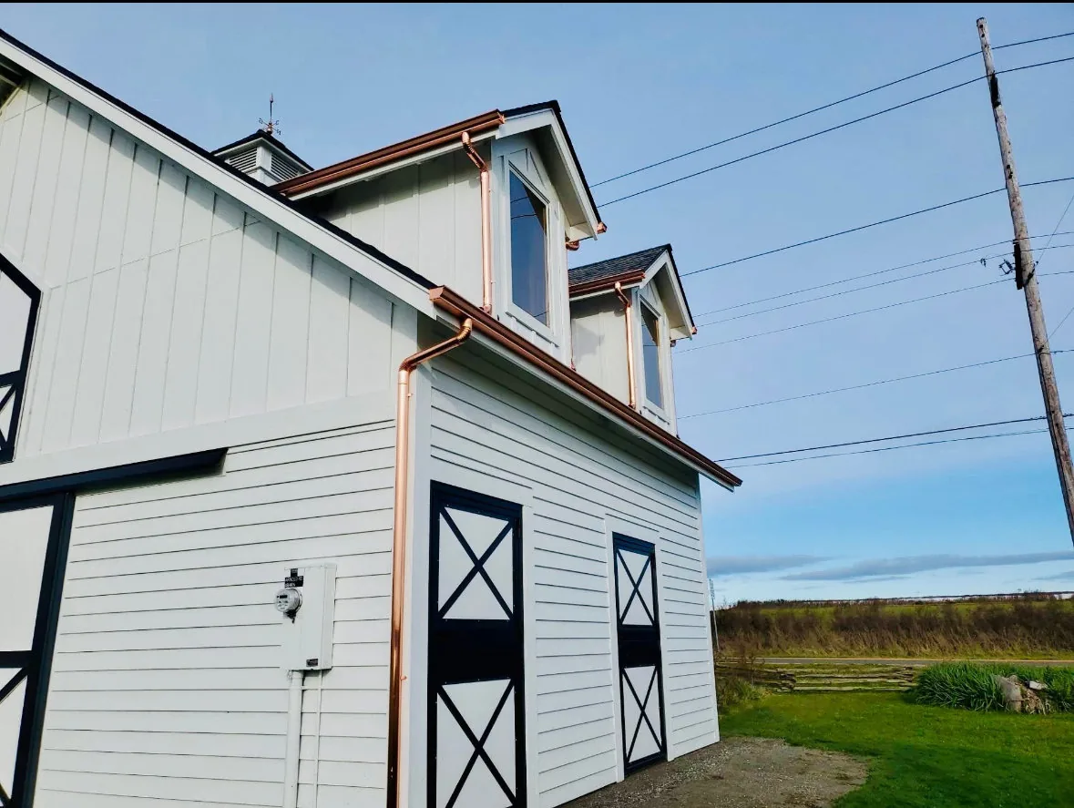 Copper seamless gutters finished on a classic white farmhouse