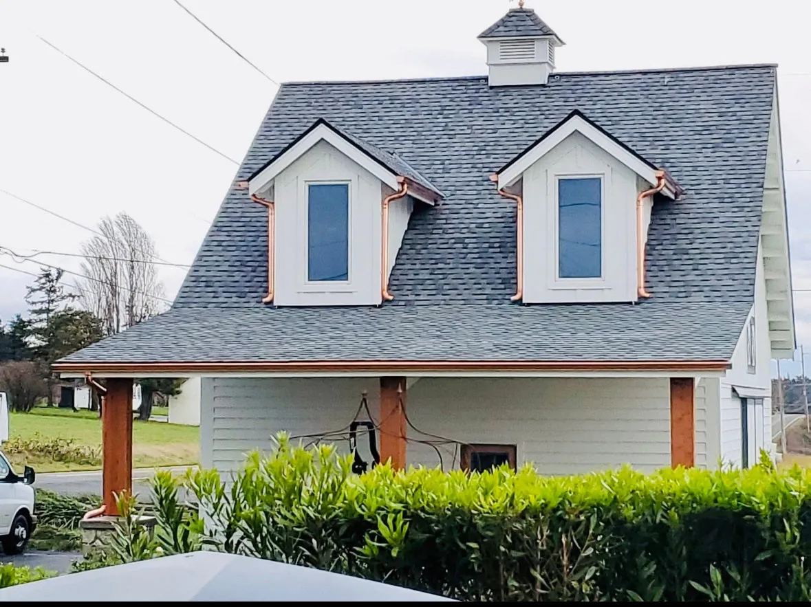 Copper gutters finished on twin dormers of a shake-roof home