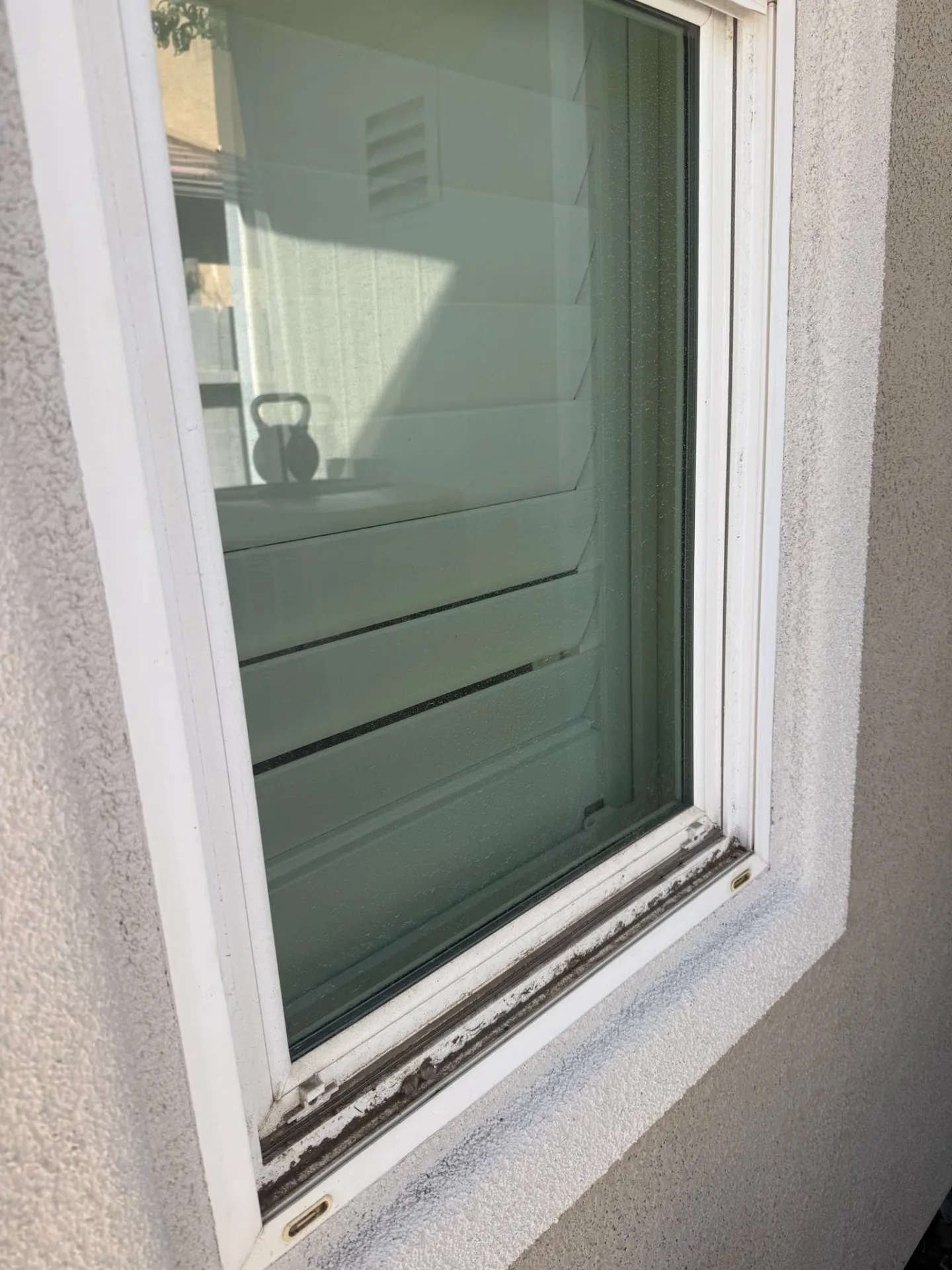 Close-up of a dust-caked window track on a Sacramento home before cleaning